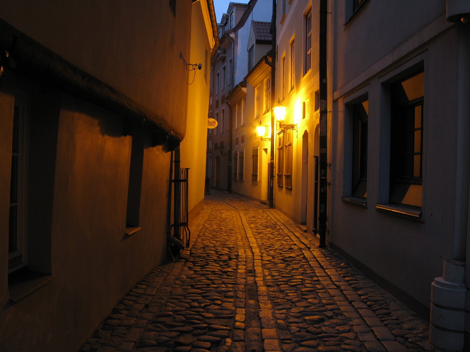 Cobbled street in the old town of Riga at dusk, with warmly lit building façades